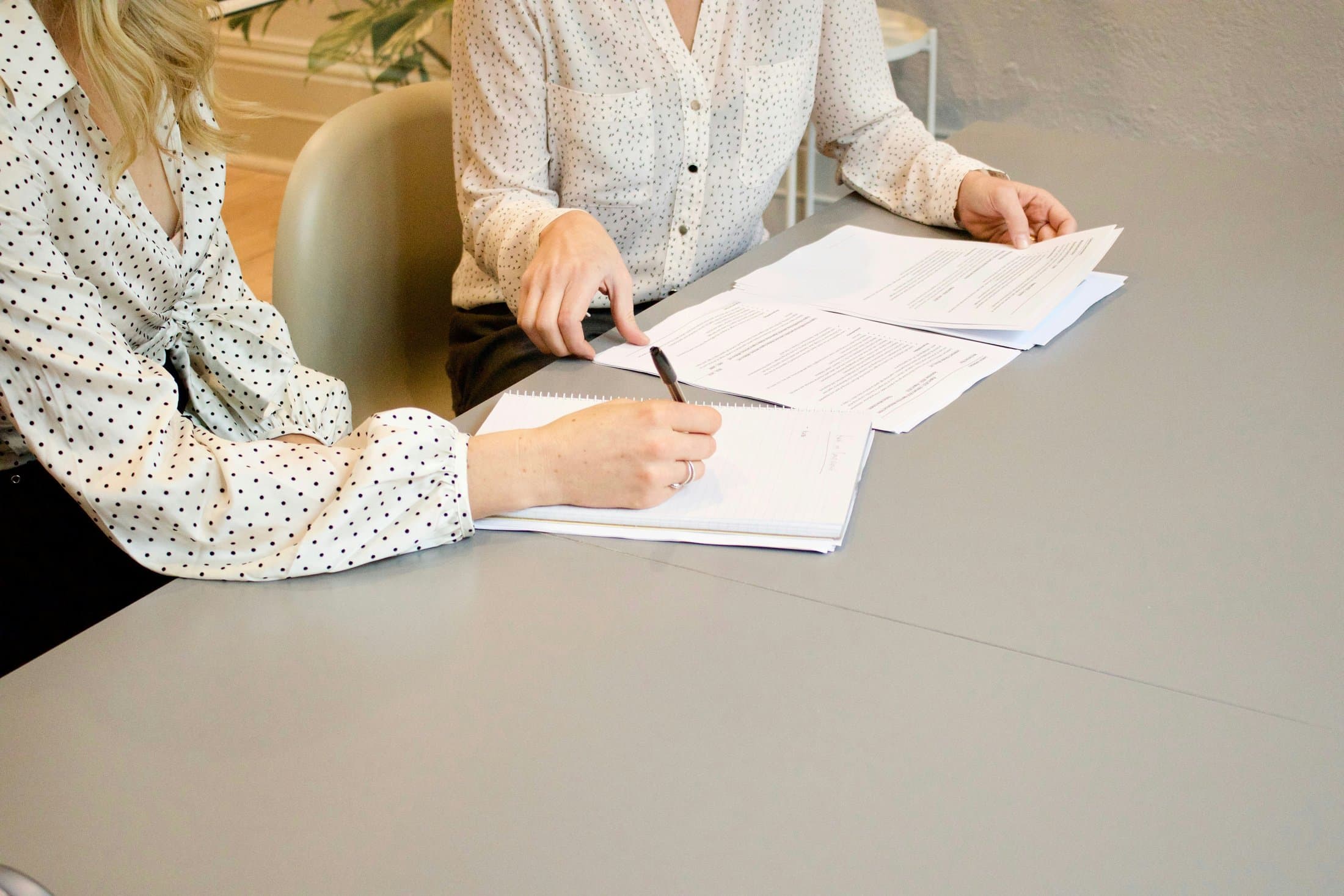 Dos profesionales firmando documentos en una mesa